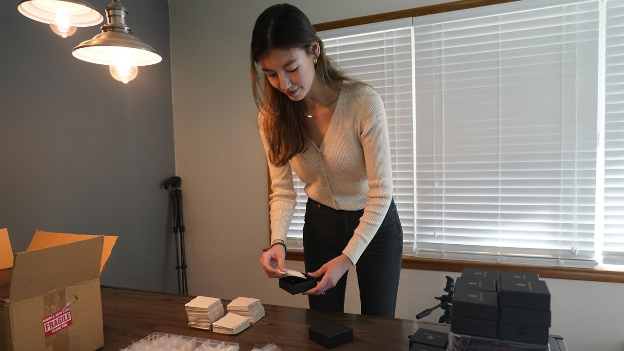 Hannah Nash places jewelry in a box that will be shipped out, Friday, Oct. 14, 2022, in Noblesville, Ind. Nash has her small business at her home. Small businesses are stocking the shelves early this holiday season and waiting to see how many gifts inflation-weary shoppers feel like giving. (AP Photo/Darron Cummings)