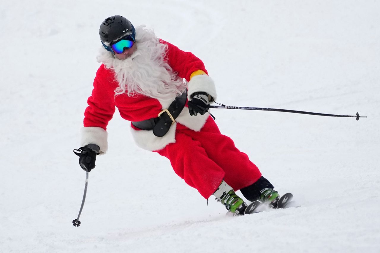 A skier dressed as Santa Claus skis for charity at the Sunday River Ski Resort, Sunday, Dec. 11, 2022, in Newry, Maine. (AP Photo/Robert F. Bukaty)
