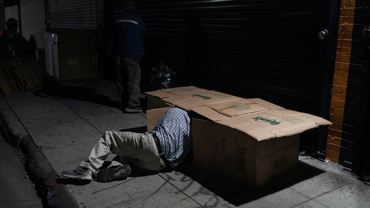 David Hernandez, a 62-year-old homeless man, crawls into his bed made with cardboard boxes in Los Angeles, late Wednesday, Dec. 14, 2022. (AP Photo/Jae C. Hong, File)