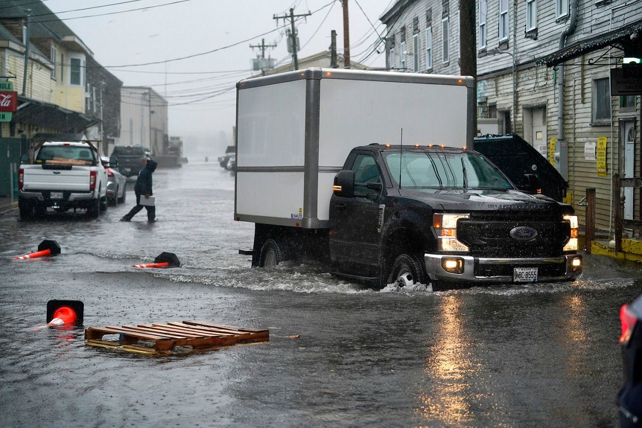 A delivery truck drives through floodwaters on the Portland, Maine, waterfront during a powerful winter storm, Friday, Dec. 23, 2022. (AP Photo/Robert F. Bukaty)