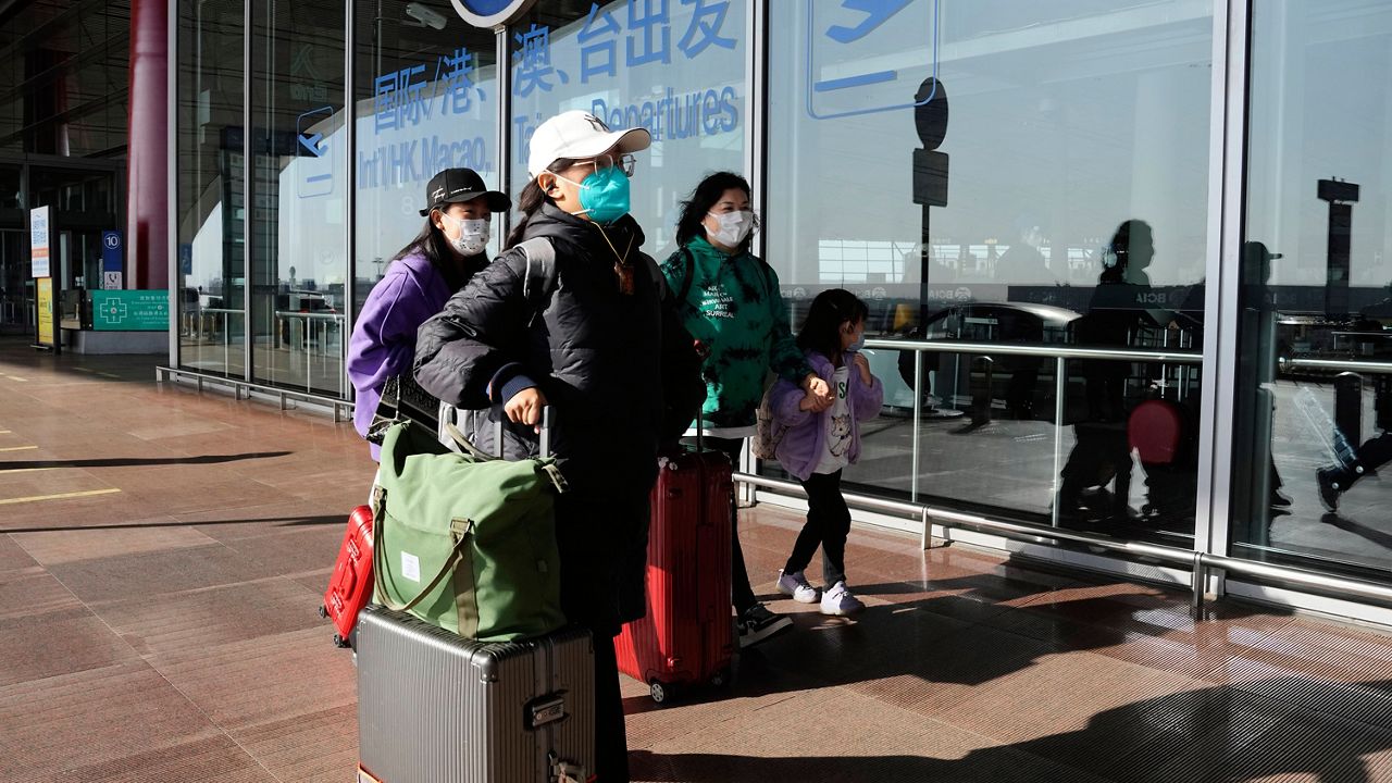 Passengers wearing masks walk through the Capital airport terminal in Beijing on Dec. 13, 2022. (AP Photo/Ng Han Guan)