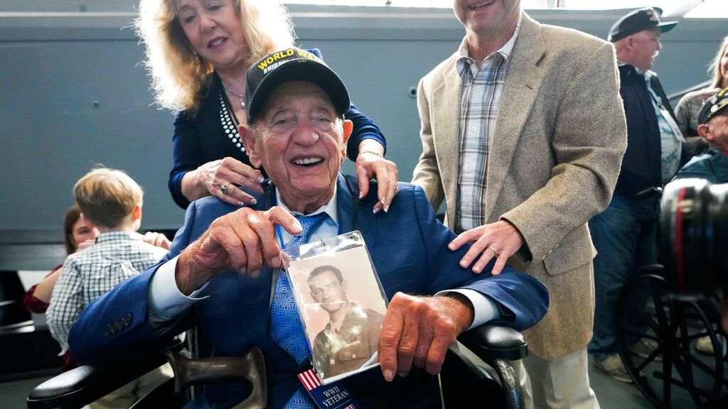 World War II veteran Joseph Eskenazi, who at 104 years and 11 months old is the oldest living veteran to survive the attack on Pearl Harbor, holds a photo of his younger self, at an event celebrating his upcoming 105th birthday at the National World War II Museum in New Orleans, Wednesday, Jan. 11, 2023. (AP Photo/Gerald Herbert)