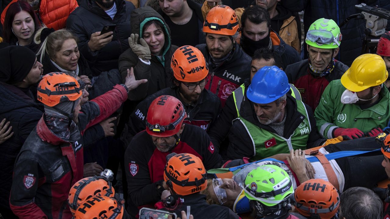 Raziye Kilinc is carried through a crowd on a stretcher after she was rescued under a destroyed building as her daughter, center, with the green black hood, waves in Iskenderun, southeastern Turkey, Friday, Feb. 10, 2023. A married couple was pulled from beneath the rubble of a collapsed building in Iskenderun after spending 109 hours buried within a small crevice. (AP Photo/Petros Giannakouris)