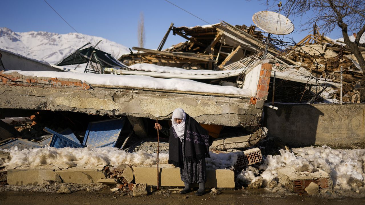 Zehra Kurukafa walks past a destroyed house in the village of Polat, Turkey, Sunday, Feb. 12, 2023. (AP Photo/Francisco Seco)