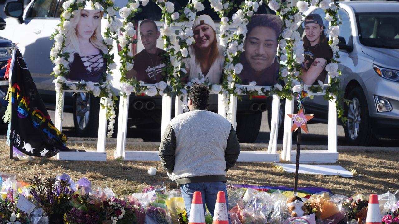 A person pauses to pay respects as portraits of the victims of a mass shooting at a gay nightclub are displayed at a makeshift memorial Nov. 22, 2022, near the scene in Colorado Springs, Colo. (AP Photo/David Zalubowski)