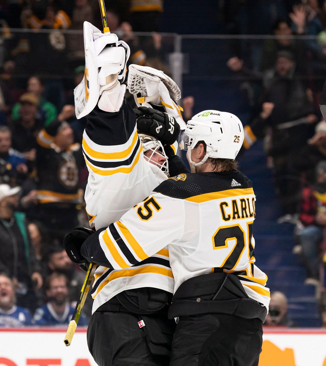 Boston Bruins goalie Linus Ullmark, left, celebrates his empty-net goal against the Vancouver Canucks with Brandon Carlo in Vancouver, British Columbia, on Saturday, Feb. 25. (Rich Lam/The Canadian Press via AP)