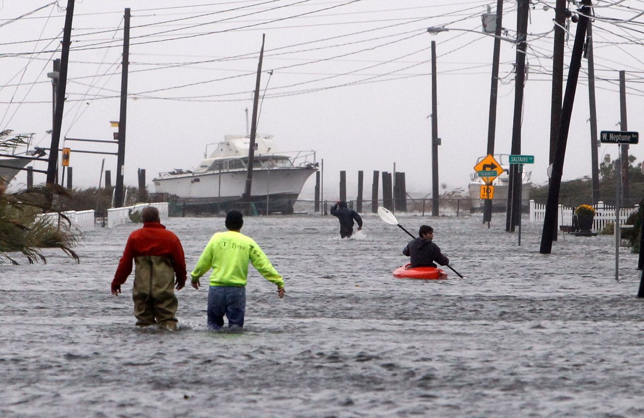 People wade and paddle down a flooded street as Hurricane Sandy approaches, Monday, Oct. 29, 2012, in Lindenhurst, N.Y. Gaining speed and power through the day, the storm knocked out electricity to more than 1 million people and figured to upend life for tens of millions more. (AP Photo/Jason DeCrow)