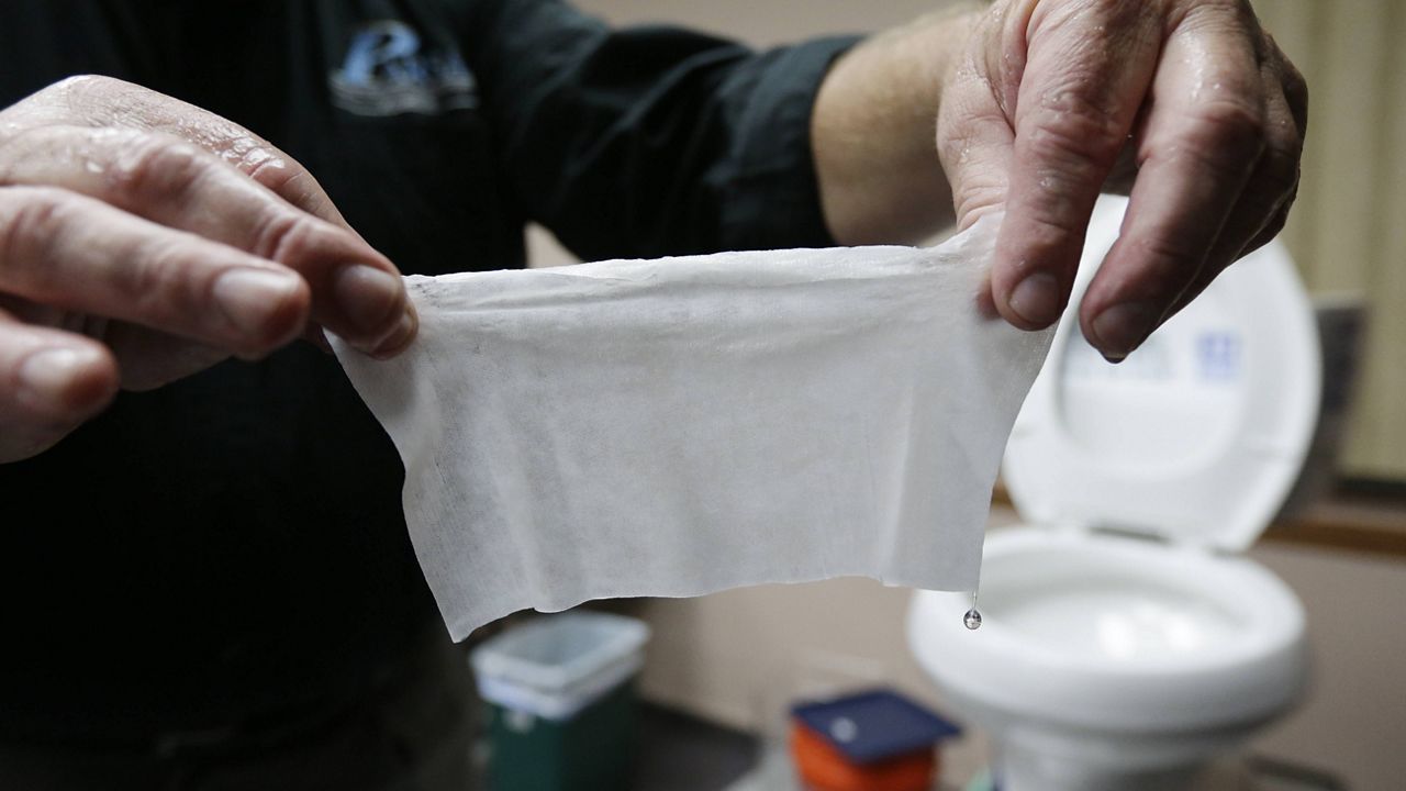 In this photograph taken Sept. 20, 2013, in Middlesex, N.J., Rob Villee, executive director of the Plainfield Area Regional Sewer Authority in New Jersey, holds up a wipe he flushed through his test toilet in his office. (AP Photo/Julio Cortez)