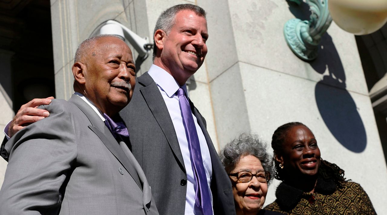 Former New York City Mayor David Dinkins, left, and current Mayor Bill de Blasio, pose for photographers with their wives Joyce Dinkins, second from right, and Chirlane McCray during a ceremony to rename the Manhattan Municipal Building to the David N. Dinkins Building, Thursday, Oct. 15, 2015, in New York. 
