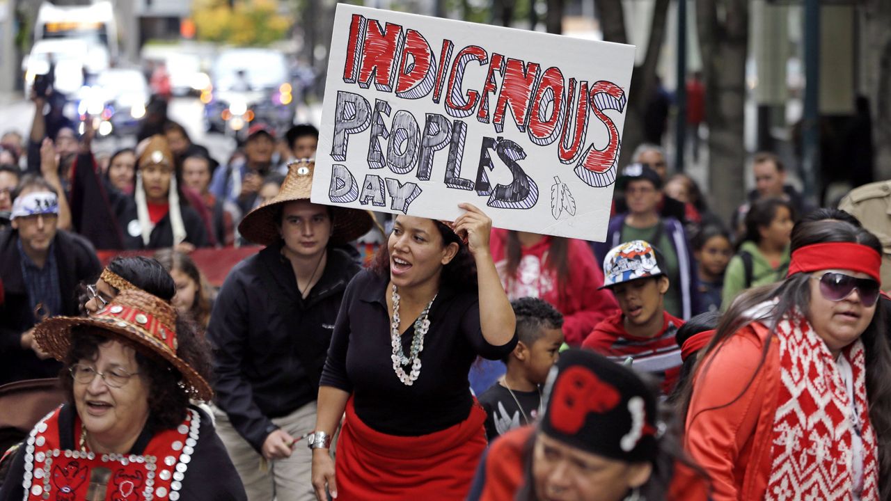 Miriam Zmiewski-Angelova, center, holds a sign for Indigenous Peoples' Day during a demonstration and march on Oct. 12, 2015, in Seattle. (AP Photo/Elaine Thompson, File)