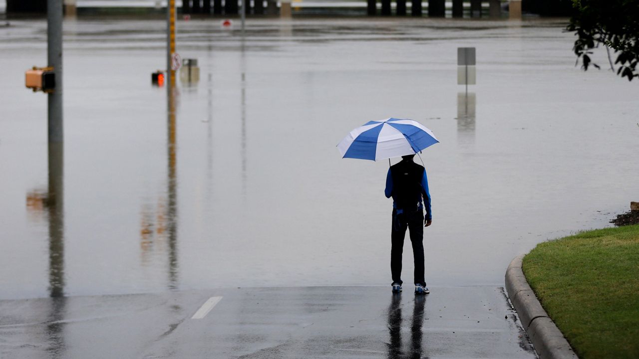 A man surveys floodwaters caused by heavy rains, Saturday, May 25, 2013, in San Antonio. The city has received torrential rains since Friday evening and officials say numerous roads have been closed because of flash flooding. (AP Photo/Eric Gay)