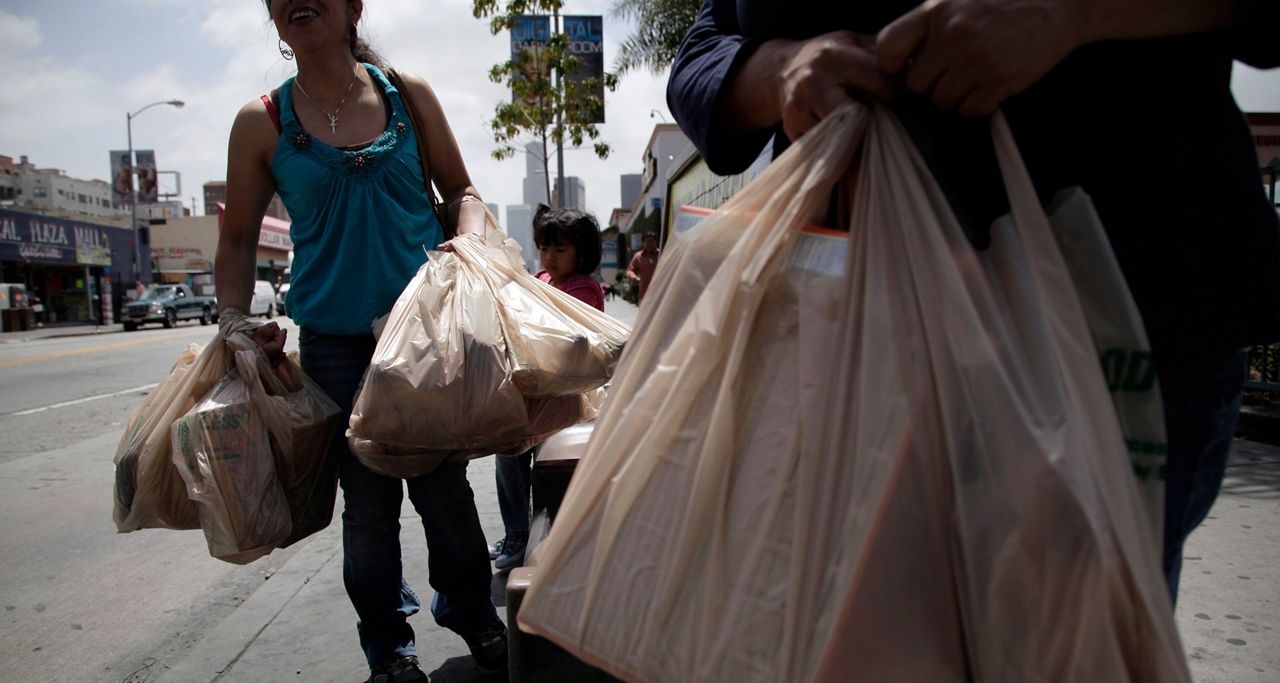 People carry bags of groceries. (AP Photo)