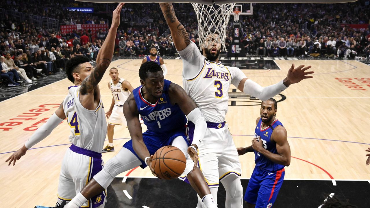 Los Angeles Clippers guard Reggie Jackson, second from left, tries to pass while under pressure from Los Angeles Lakers guard Danny Green, left, and forward Anthony Davis during the second half of an NBA basketball game Sunday, March 8, 2020, in Los Angeles. The Lakers won 112-103. (AP Photo/Mark J. Terrill)