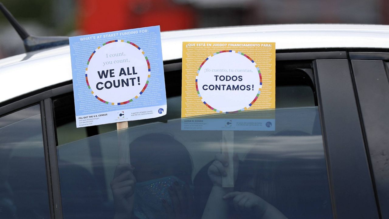 In this June 25, 2020, file photo, two young children hold signs through the car window that make reference to the 2020 U.S. (AP Photo/Tony Gutierrez, File)