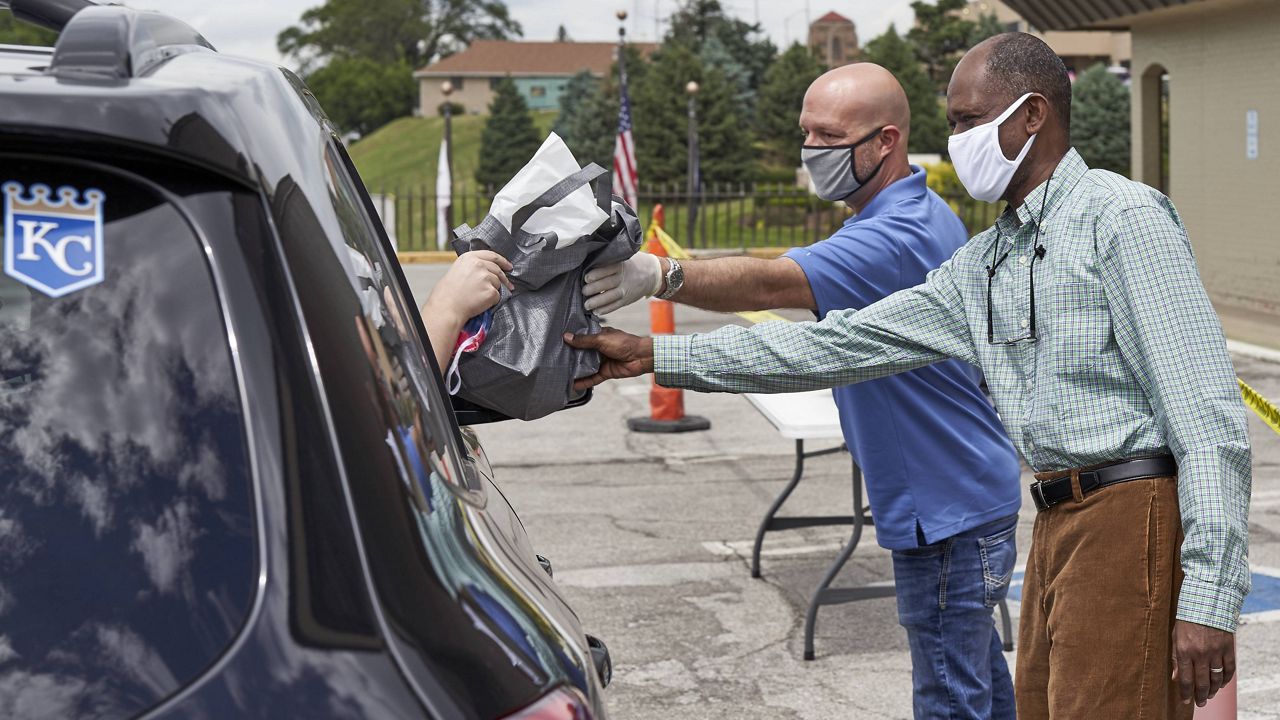 A motorist is handed a bag containing information about open positions at a drive-thru job fair in Omaha, Neb., Wednesday, July 15, 2020. (AP Photo/Nati Harnik)