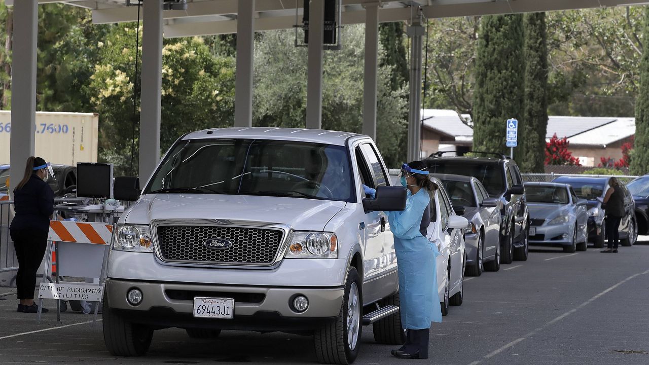 Healthcare workers take information and samples from people waiting to be tested for Covid-19 Tuesday, July 21, 2020, in Pleasanton, Calif. This center was closed mid-day due to maximum capacity of people waiting. (AP Photo/Ben Margot)