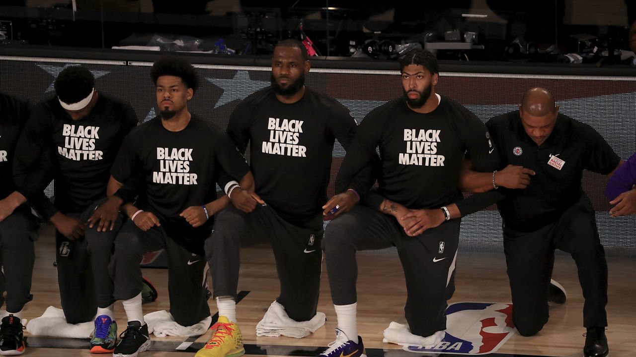 File - LeBron James and Anthony Davis wear Black Lives Matter shirts as they kneel with teammates during the national anthem prior to an NBA basketball game against the Los Angeles Clippers, Thursday, July 30, 2020, in Lake Buena Vista, Fla. (Mike Ehrmann/Pool Photo via AP)