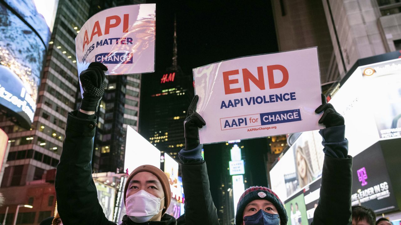 People hold signs in support of Asian American Pacific Islander communities while attending a candlelight vigil in honor of Michelle Alyssa Go, a victim of a recent subway attack, at Times Square on Tuesday, Jan. 18, 2022, in New York. (AP Photo/Yuki Iwamura)