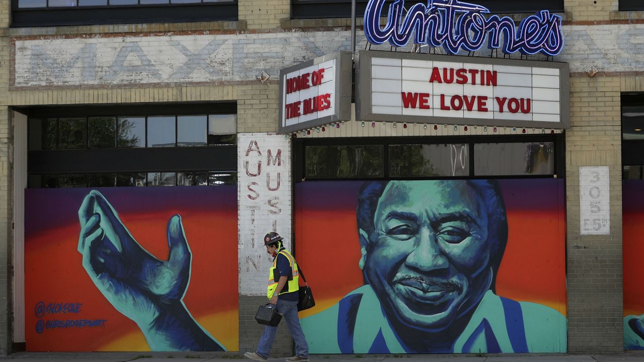 A construction worker walks past a mural painted on a boarded-up business closed due to the COVID-19 pandemic, Monday, April 27, 2020, in Austin, Texas. (AP Photo/Eric Gay)