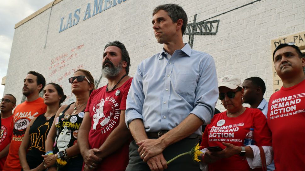 Muralist Manuel Oliver, whose son was killed in the Parkland Florida shooting, at center in red, is flanked by his wife and daughter, left, in black, and Democratic presidential candidate Beto O'Rourke, right in blue, during an unveiling ceremony for Oliver's mural, in El Paso, Texas, Sunday, Aug. 4, 2019. The mural, which advocates for humane treatment of immigrants, became a memorial after more than 20 people were killed on Saturday in an attack that officials are investigating as a hate crime. O'Rourke is holding a sunflower as a symbolic gesture to Oliver's son, who is said to have carried sunflowers the day he died. (AP Photo/Cedar Attanasio)