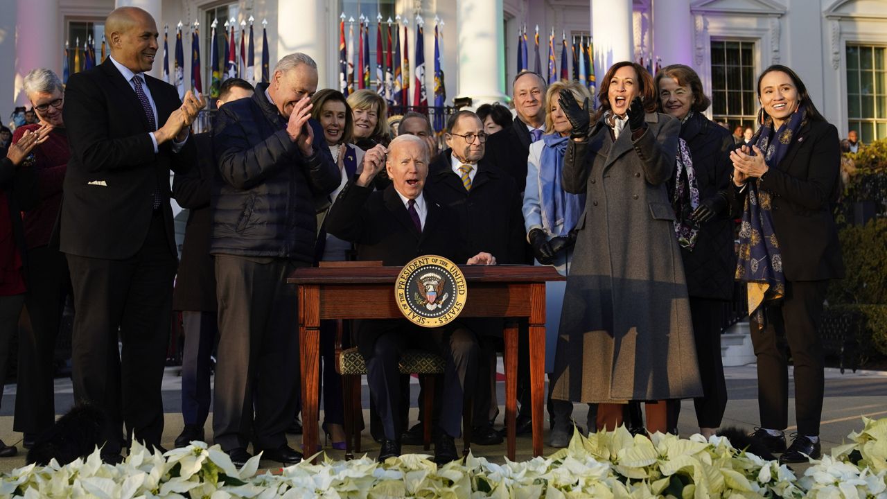 President Joe Biden raise his pen and reacts to applauds after signing the Respect for Marriage Act, Tuesday, Dec. 13, 2022, on the South Lawn of the White House in Washington. (AP Photo/Patrick Semansky)