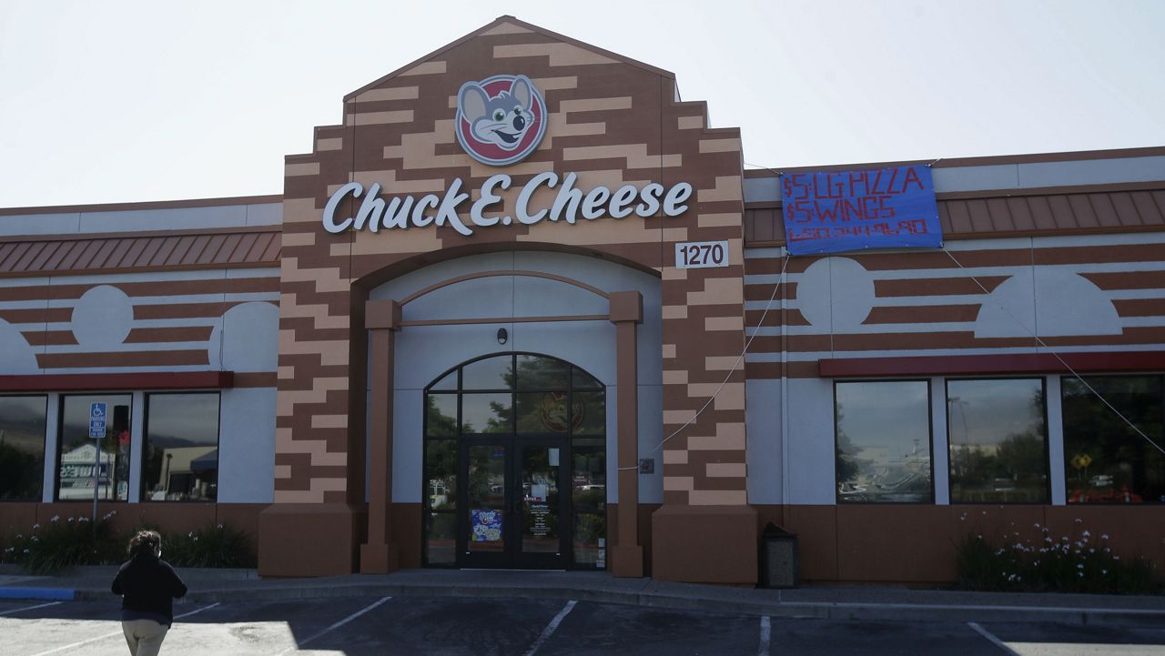 A woman walks toward the entrance to a Chuck E. Cheese restaurant in San Bruno, Calif., Thursday, June 25, 2020. Chuck E. Cheese's parent company, CEC Entertainment, filed for bankruptcy Thursday. The 43-year-old chain, which drew kids with pizza, video games and a singing mouse mascot, was struggling even before the coronavirus pandemic. But it said the prolonged closure of many outlets due to coronavirus restrictions led to Thursday's Chapter 11 filing. (AP Photo/Jeff Chiu)