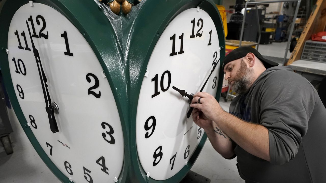 FILE: Clock technician Dan LaMoore, of Woonsocket, R.I., adjusts clock hands on a large outdoor clock under construction at Electric Time Company, Tuesday, Nov. 2, 2021, in Medfield, Mass. (AP Photo/Steven Senne)