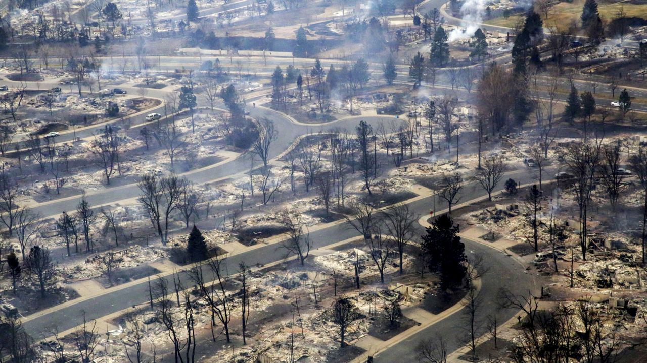 FILE - Smoke rises in a neighborhood of Boulder County that was destroyed by a wildfire. (Hart Van Denburg/Colorado Public Radio via AP, Pool, Fil)