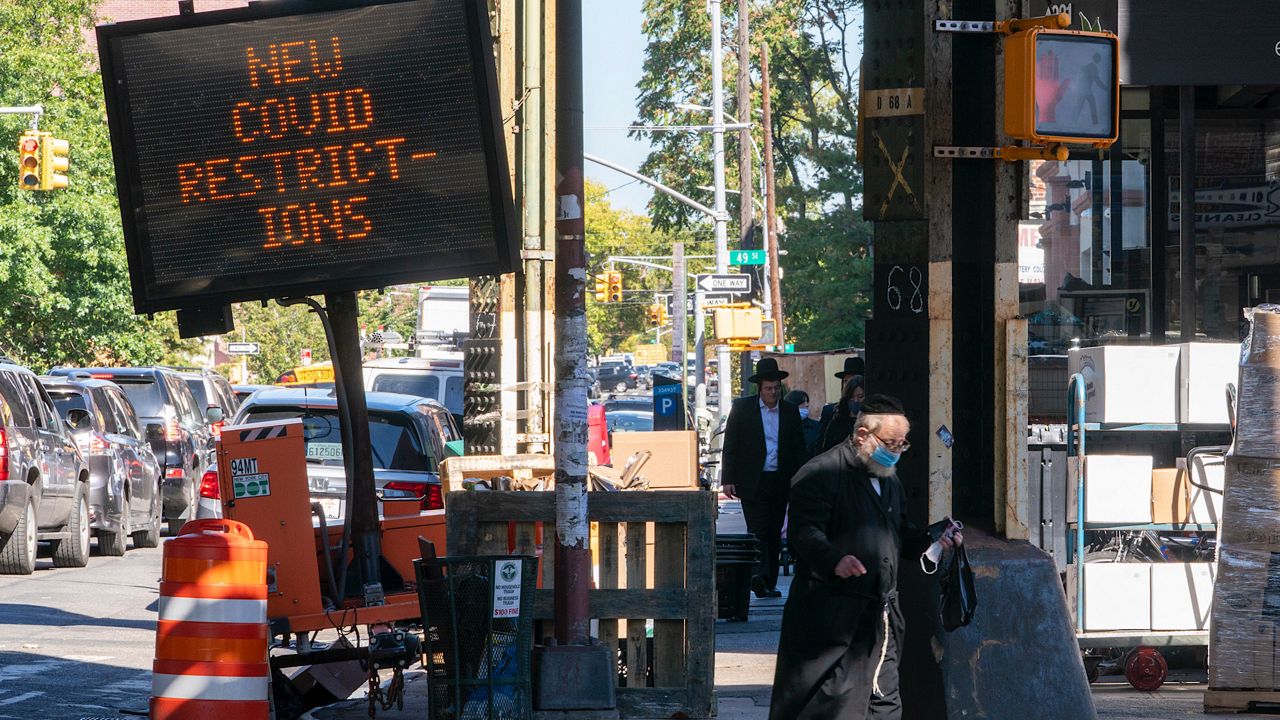 A traffic sign warns of new COVID-19 restrictions on New Utrecht Ave. in the Orthodox Jewish neighborhood of Borough Park, Wednesday, Oct. 14, 2020. (AP Photo/Mary Altaffer)