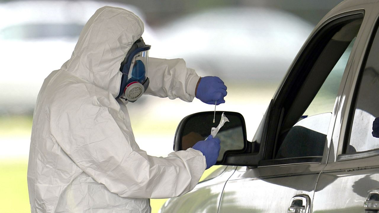 A medical professional takes a sample from a drive-thru patient for testing at a newly opened free COVID-19 testing site operated by United Memorial Medical Center Thursday, April 2, 2020, in Houston. The new coronavirus causes mild or moderate symptoms for most people, but for some, especially older adults and people with existing health problems, it can cause more severe illness or death. (AP Photo/David J. Phillip)