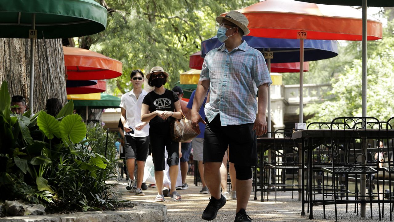 Visitors, some wearing masks to protect against the spread of COVID-19, walk along the River Walk in San Antonio, Wednesday, June 24, 2020. (AP Photo/Eric Gay)