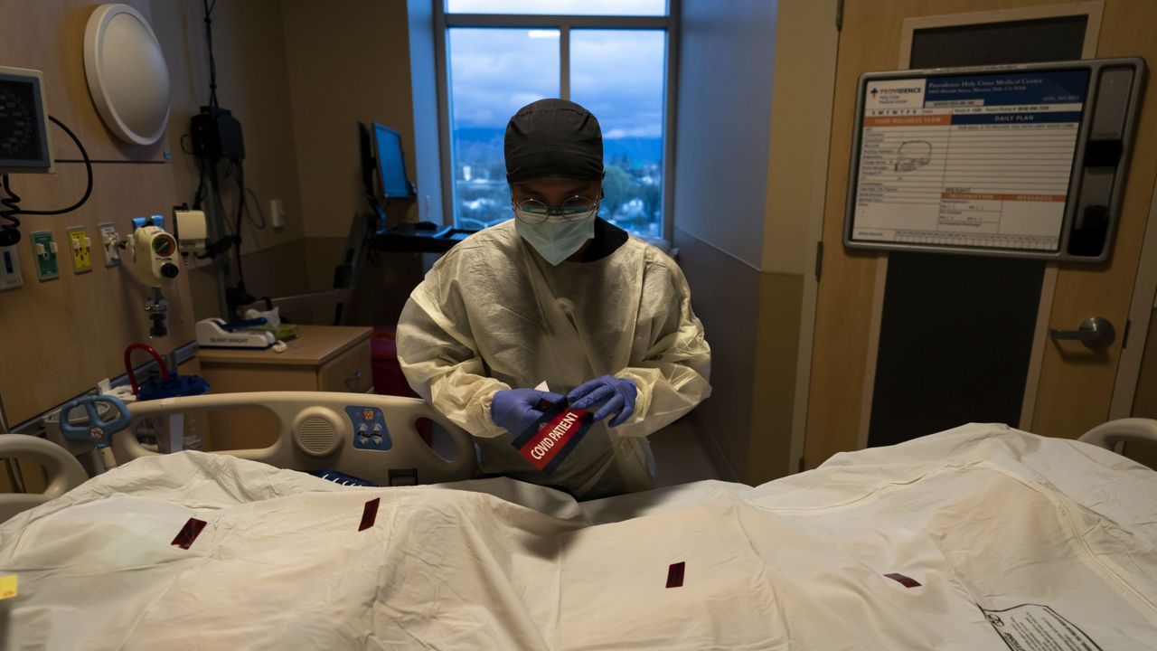 Registered nurse Bryan Hofilena attaches a "COVID Patient" sticker on a body bag of a patient who died of coronavirus at Providence Holy Cross Medical Center in Los Angeles, on Dec. 14, 2021. (AP Photo/Jae C. Hong, File )
