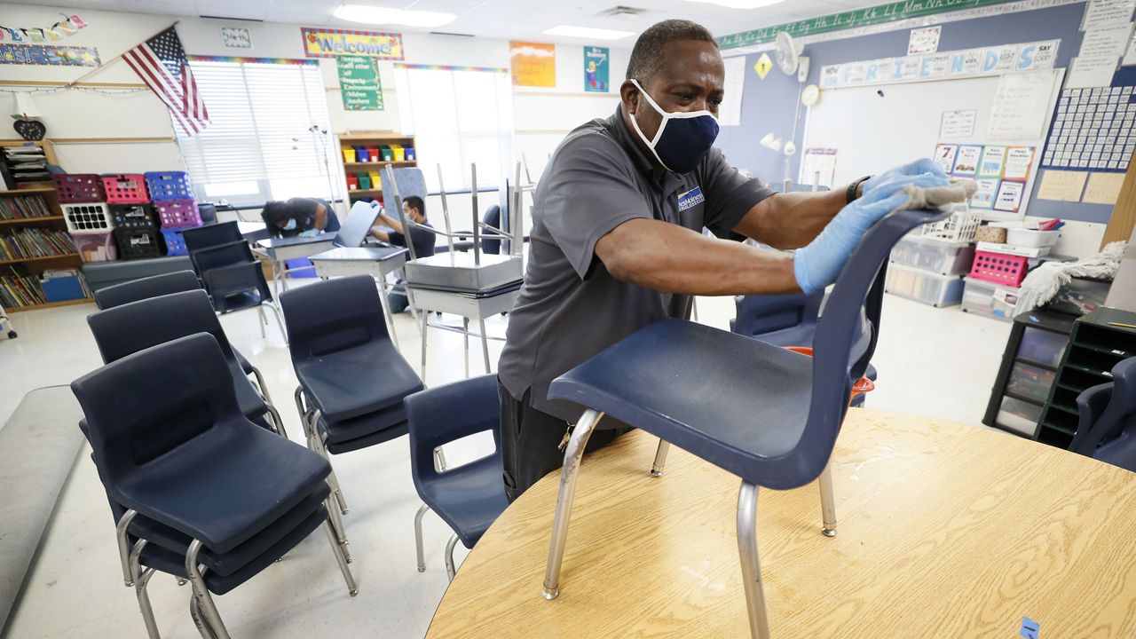 Des Moines Public Schools custodian cleans chairs in a classroom at Brubaker Elementary School, Wednesday, July 8, 2020, in Des Moines, Iowa. (AP Photo/Charlie Neibergall)