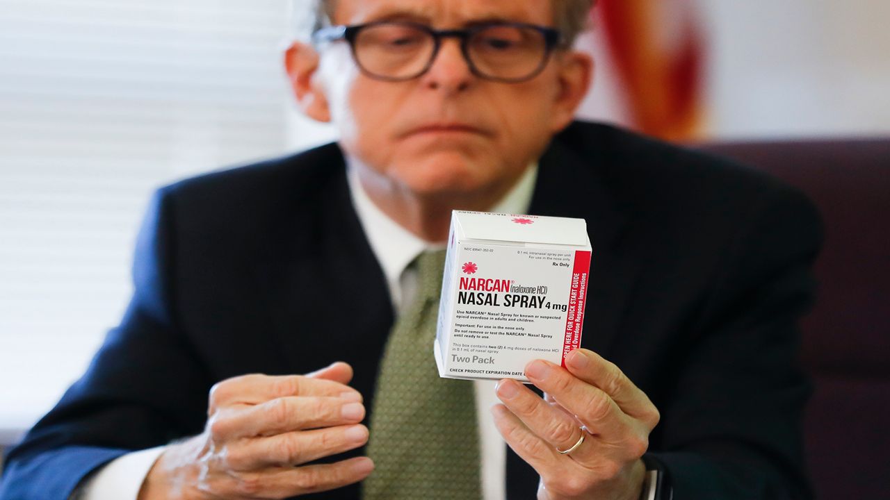 Ohio Gov. Mike DeWine holding a box of Narcan