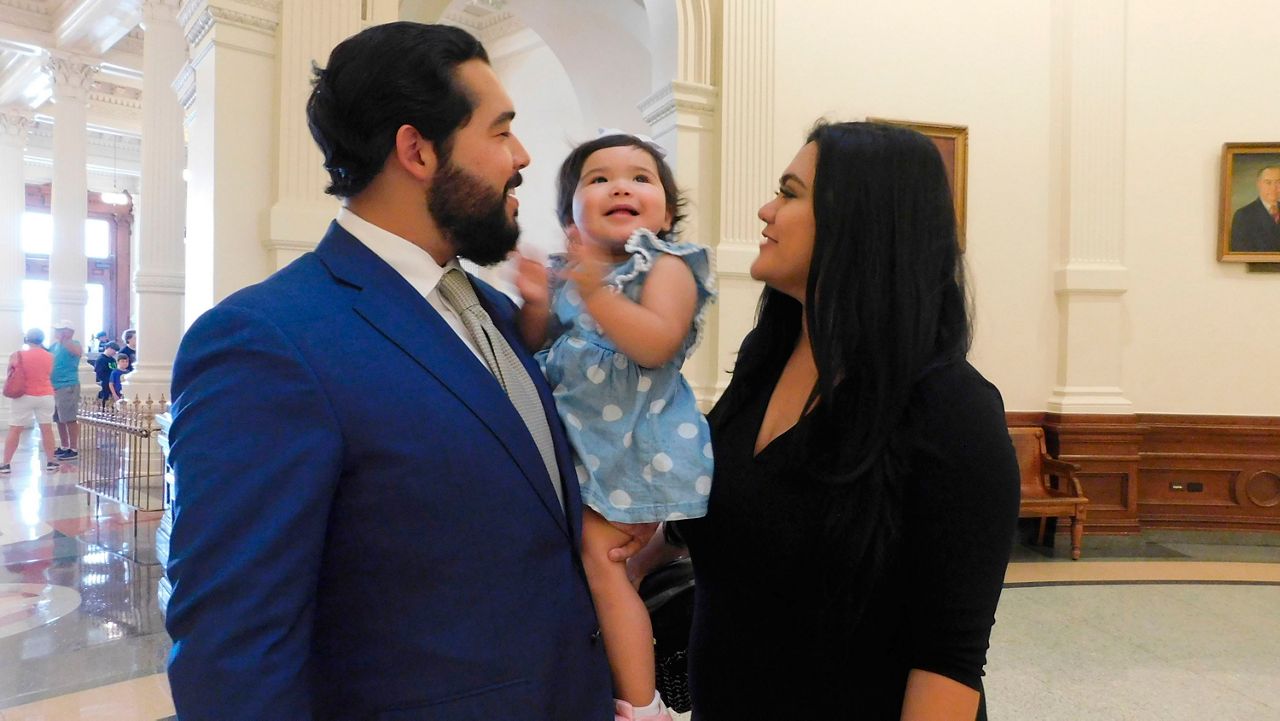 Donovon Rodriguez, chief of staff for Texas state Rep. Ray Lopez, walks around the Texas capitol with his wife, Jenny Tavarez, and daughter, Evelyn Belle Rodriguez, for whom he is the sole provider, Monday, July 26, 2021 in Austin, Texas. Rodriguez could lose his job by Sept. 1, if legislative budget funding is not restored. Texas. (AP Photo/Acacia Coronado)