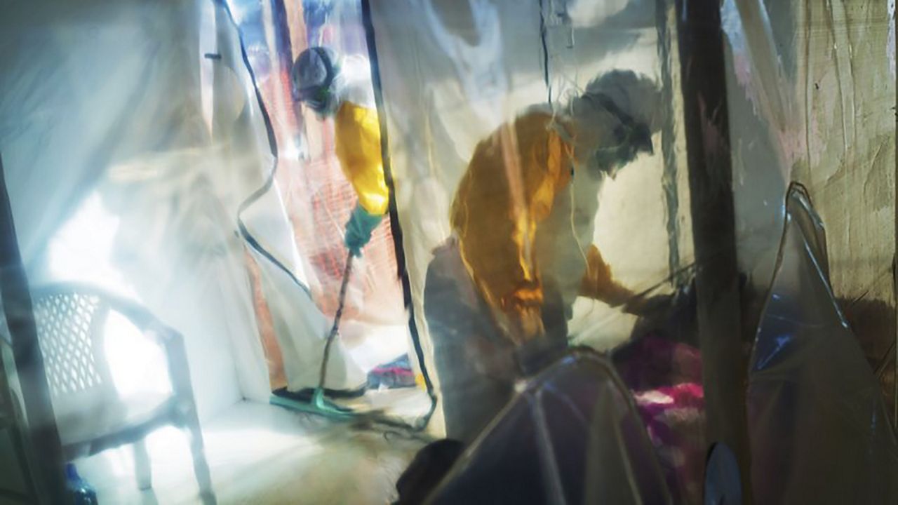  In this Saturday, July 13, 2019 file photo, health workers wearing protective suits tend to an Ebola victim kept in an isolation tent in Beni, Democratic Republic of Congo. A top official at the World Health Organization has said on Friday, March 12, 2021 that a genetic analysis of the ongoing Ebola outbreak in Guinea suggests it may have been sparked by a survivor of the devastating West Africa epidemic that ended five years ago. (AP Photo/Jerome Delay, file)