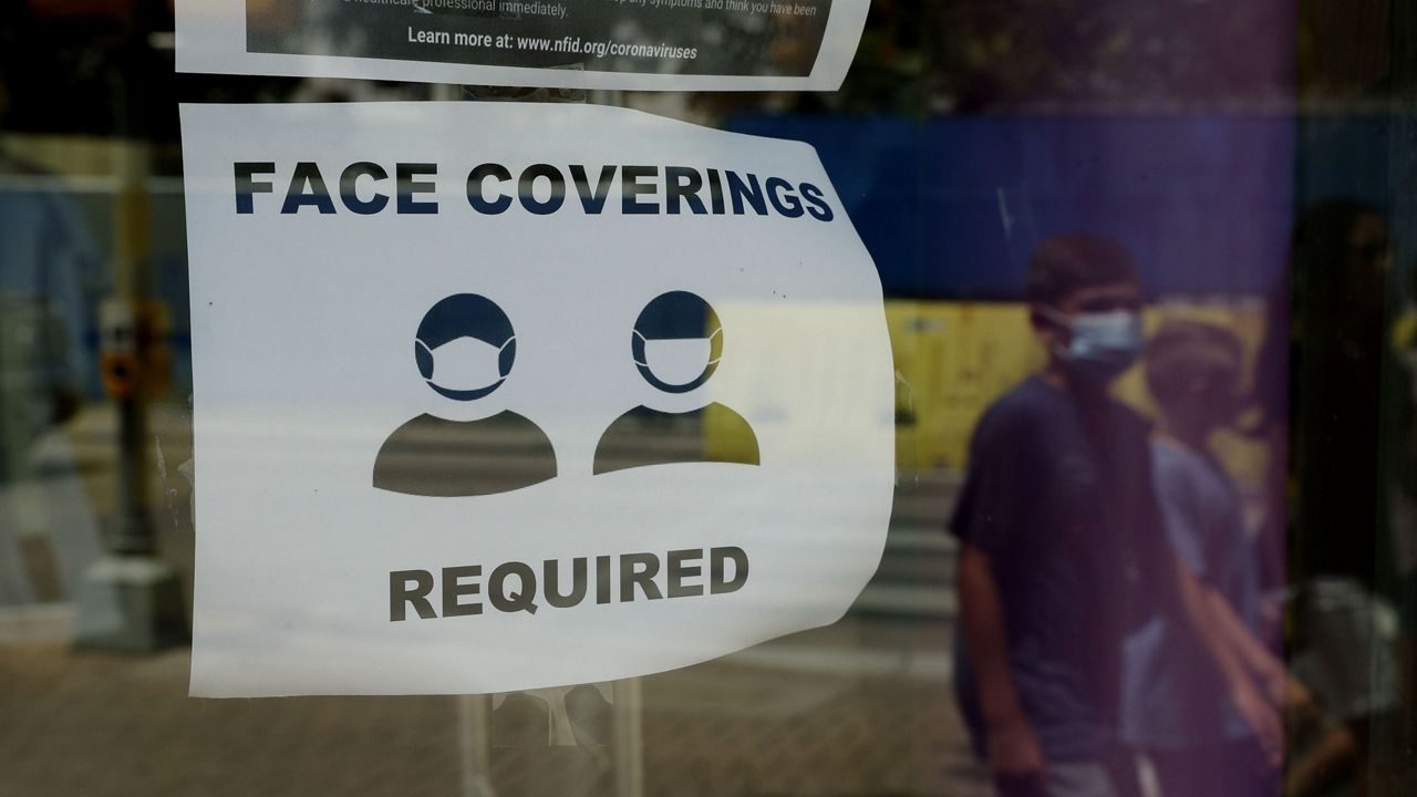 A visitor wearing a mask to protect against the spread of COVID-19 passes a sign requiring masks, Tuesday, July 7, 2020, in San Antonio. (AP Photo/Eric Gay)