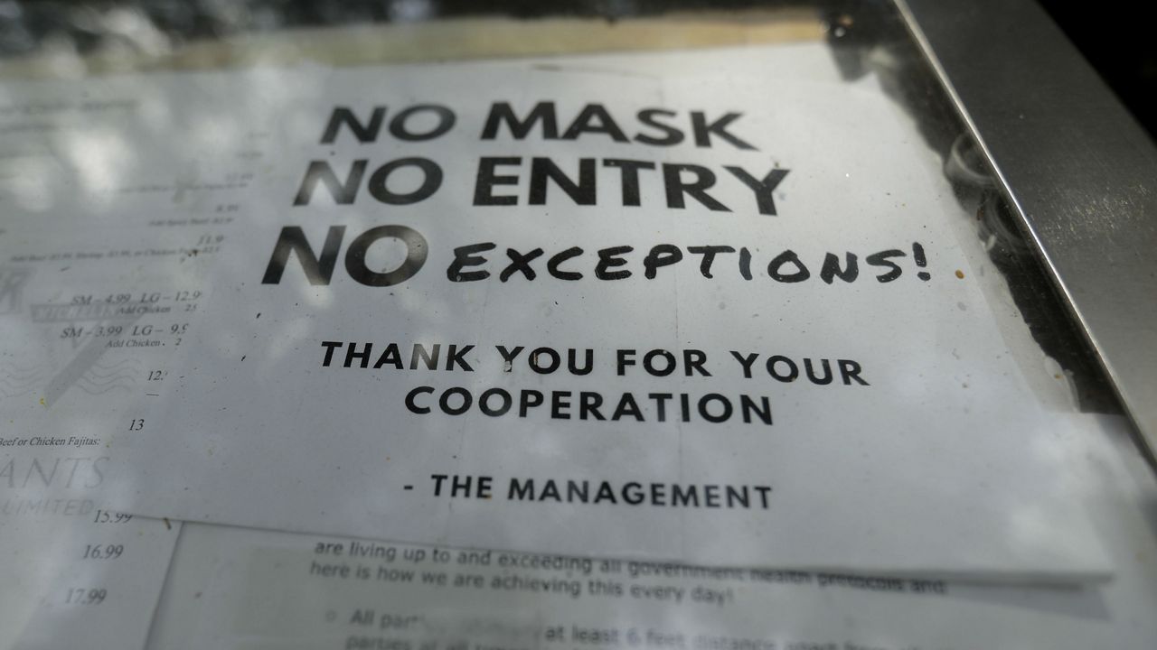 A sign requiring face masks to protect against the spread of COVID-19 is seen at a restaurant, Tuesday, July 7, 2020, in San Antonio. (AP Photo/Eric Gay)