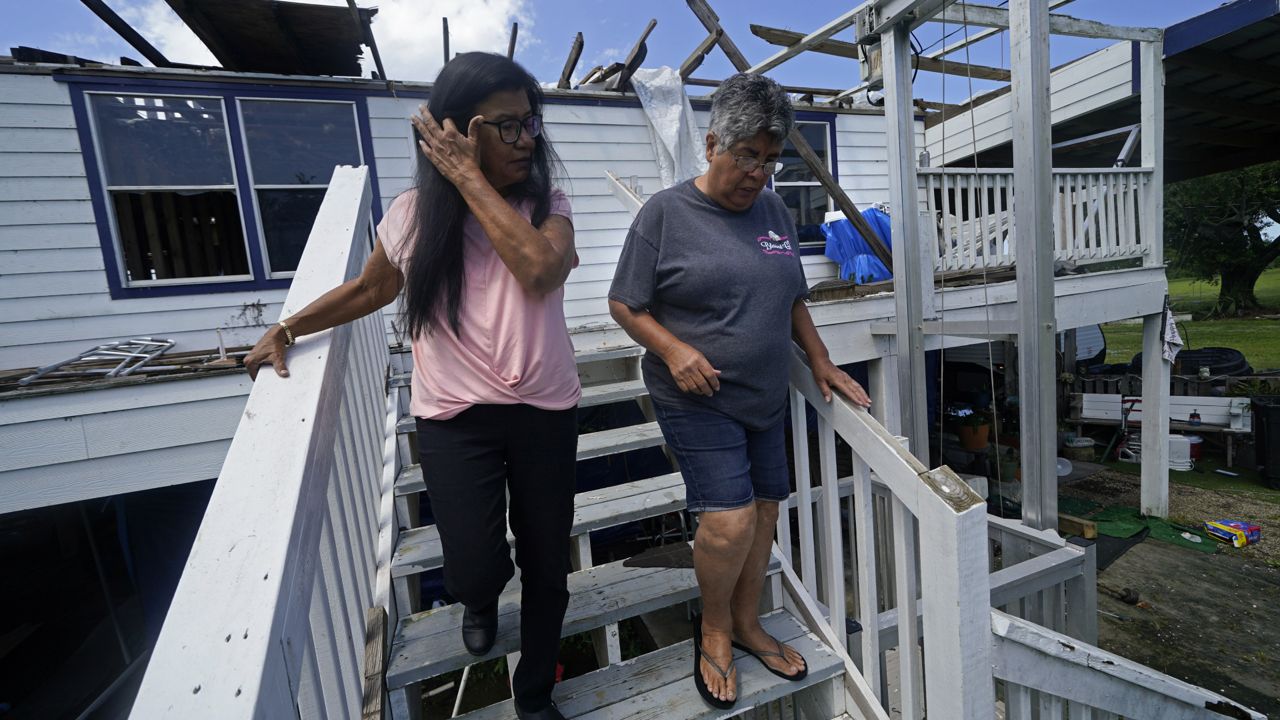 FILE - Louise Billiot, left, a member of the United Houma Nation Indian tribe, walks around the home of her friend and tribal member Irene Verdin, which was heavily damaged from Hurricane Ida nine months before, along Bayou Pointe-au-Chien, in Pointe-aux-Chenes, La., on May 26, 2022. (AP Photo/Gerald Herbert, File)