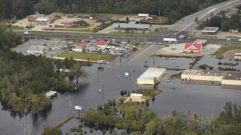 FILE - In this Monday, Sept. 24, 2018 photo, flood waters from the Neuse River cover the area a week after Hurricane Florence in Kinston, N.C. Monday Sept. 24, 2018. Hot real estate markets have made some homeowners wary of participating in voluntary flood buyout programs, impacting efforts to move people away from flooding from rising seas, intensifying hurricanes and more frequent storms. Flood buyout programs typically purchase flood-prone homes, raze them and turn the property into green space. (Ken Blevins/The Star-News via AP)