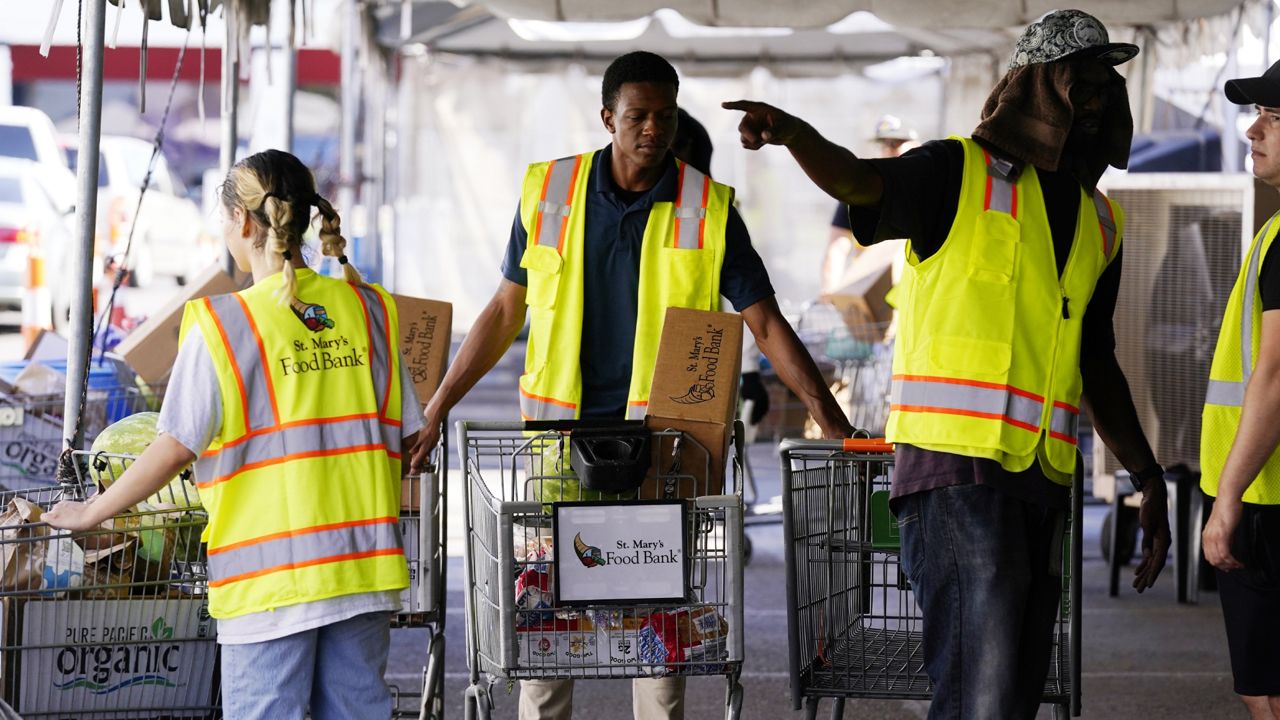 Volunteers position grocery carts to fill up vehicles with food boxes at the St. Mary's Food Bank Wednesday, June 29, 2022, in Phoenix. (AP Photo/Ross D. Franklin)