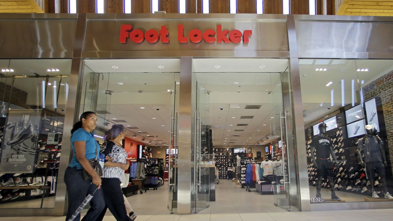 FILE - In this Aug. 22, 2017 file photo, shoppers walk past a Foot Locker store in Hialeah, Fla. (AP Photo/Alan Diaz)