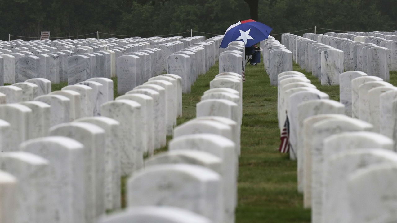A visitor sits at a gravesite at Fort Sam Houston National Cemetery in San Antonio, Tuesday, April 7, 2020. (AP Photo/Eric Gay)