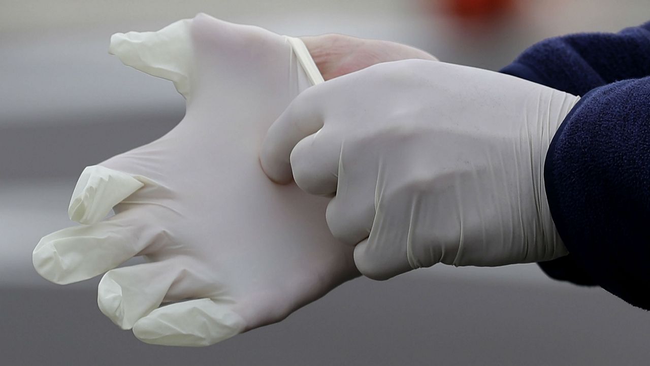 A person putting on latex gloves. (AP Photo/Nam Y. Huh)
