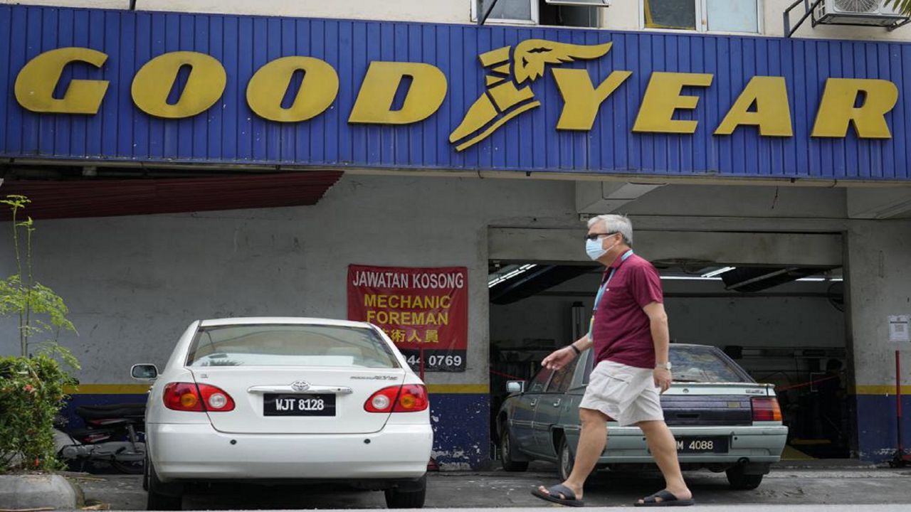 A man wearing a face mask walks in front of a Goodyear shop in Bukit Jalil, outskirts of Kuala Lumpur, Malaysia, Friday, June 11, 2021.  (AP Photo/Vincent Thian)