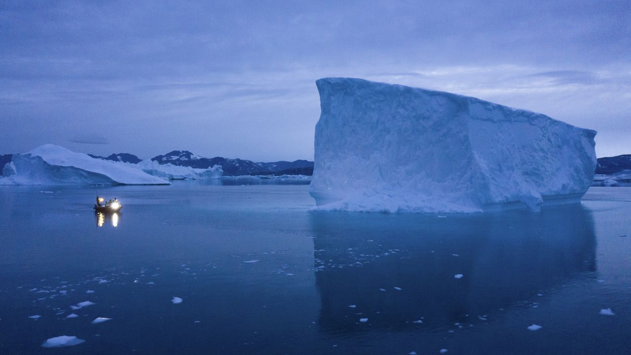 A boat navigates at night next to large icebergs in eastern Greenland on Aug. 15, 2019. (AP Photo/Felipe Dana, File)