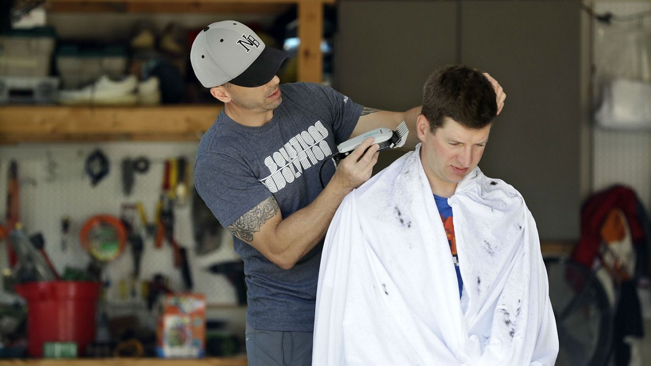 Mike Swyt, right, gets a haircut in his garage from his brother-in-law, Ryan Nolan, because barber shops are closed due to the coronavirus outbreak Sunday, April 5, 2020. (AP Photo/Mark Humphrey)