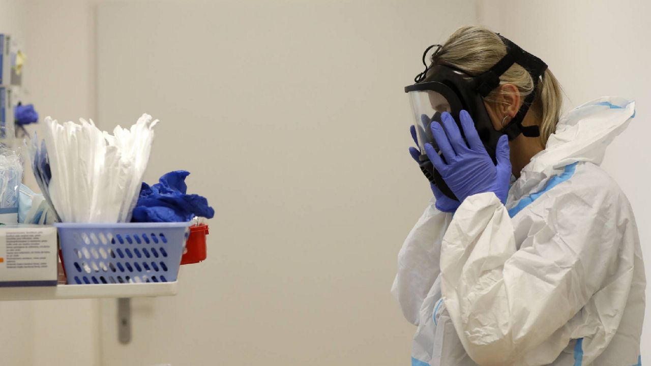 A woman puts on a face shield and PPE in a hospital (AP Image/File)
