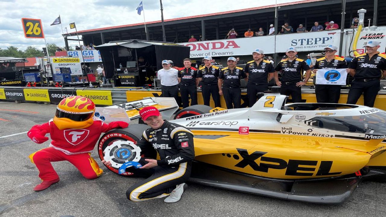 Josef Newgarden poses besides his Team Penske Chevrolet after winning the pole for the IndyCar race at Mid-Ohio Sports Car Course Saturday, July 3, 2021 in Lexington, Ohio. Newgarden will start alongside Colton Herta for Sunday’s race in an All-American driver front row.(AP Photo/Jenna Fryer)