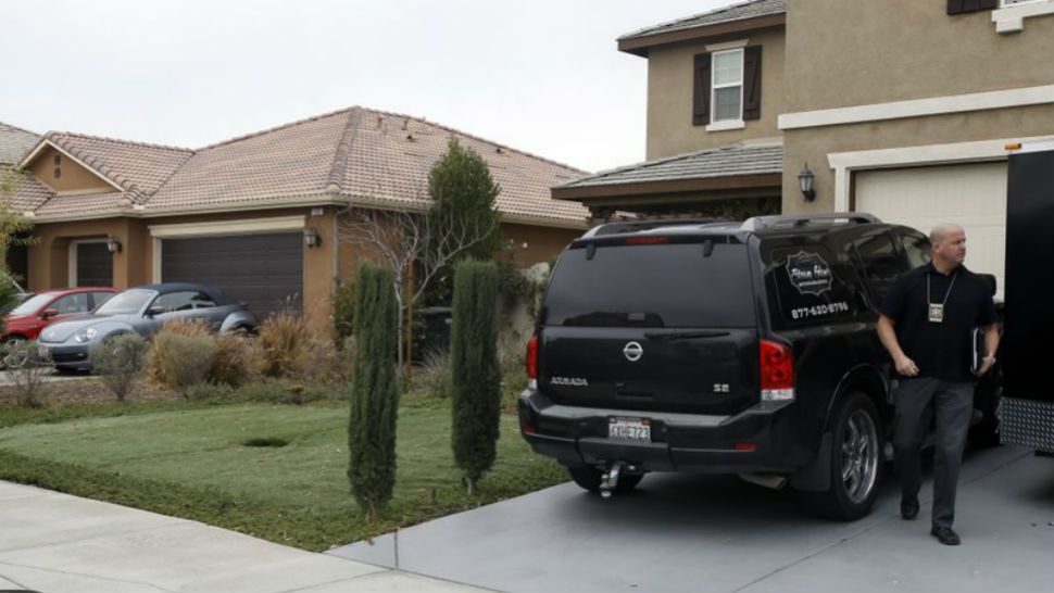 Detective walks next to a home Tuesday, Jan. 16, 2018, where police arrested a couple accused of holding 13 children captive in Perris Calif. Authorities said an emaciated teen led deputies to the California home where her 12 siblings were locked up in filthy conditions, with some of them malnourished and chained to beds. (AP Photo/Alex Gallardo)